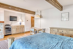 A bedroom with a bed, wooden dresser, television, and a dining area. - Lakefront getaway with Private beach access & balcony, sleeps 6 (Zephyr Cove)