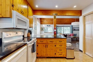 Eine moderne Küche mit Holzschränken, einer Mikrowelle, einem Herd und einem Backofen.