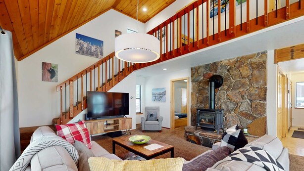 Un salon spacieux avec un grand canapé, un téléviseur, une cheminée et un escalier en bois.