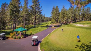Un parcours de golf avec un pavillon, un chariot de golf et une personne qui s’apprête à effectuer un putt.