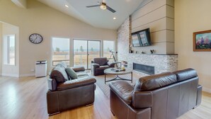 A spacious living room with leather sofas, a coffee table, and a fireplace. - New-Build Tahoe Keys Haven with Pool Table, Decks & Mountain Views - Near Beach (South Lake Tahoe)