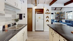 A modern kitchen with a central island, a built-in oven, and a dining area with a blue sofa and bookshelves. - Family-friendly cabin with fireplace, bikes, loft, games, & skiing nearby (South Lake Tahoe)
