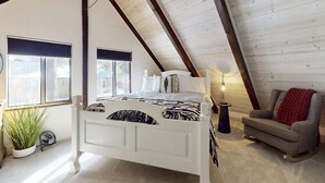 A bedroom with a white bed, a grey armchair, a red throw, and a potted plant. - Family-friendly cabin with fireplace, bikes, loft, games, & skiing nearby (South Lake Tahoe)