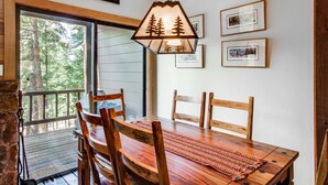 Een eetruimte met een houten tafel, stoelen en een hanglamp met een bosdecor.