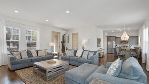 A modern living room with two sofas, a coffee table, and a kitchen in the background. - Under New Management! Designed for Family Fun w/Golf Cart&Bikes (Santa Rosa Beach)