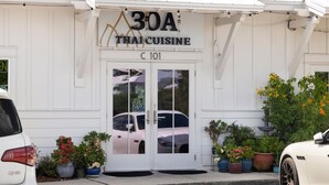 A Thai cuisine restaurant with a white facade, a double door entrance, and potted plants outside. - Under New Management! Designed for Family Fun w/Golf Cart&Bikes (Santa Rosa Beach)