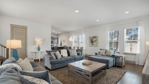 A spacious living area with a sofa set, coffee table, and a view of the kitchen and dining area. - Under New Management! Designed for Family Fun w/Golf Cart&Bikes (Santa Rosa Beach)