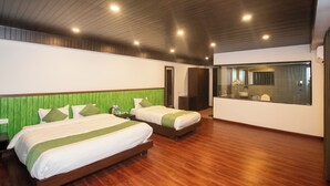 Ein Hotelzimmer mit zwei Betten, Holzboden, einer großen Decke aus Holz und einem großen Spiegel.