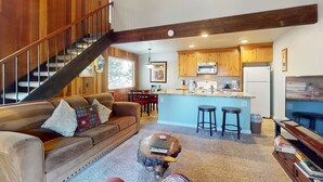 A spacious living area with a staircase, a kitchen with wooden cabinets, and a bar area. - Beautiful Condo with Shared Pool & Tennis Courts, Close to Northstar (Kings Beach)