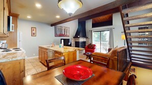 A kitchen with a dining area, wooden cabinets, a red bowl on the table, and a staircase. - Beautiful Condo with Shared Pool & Tennis Courts, Close to Northstar (Kings Beach)