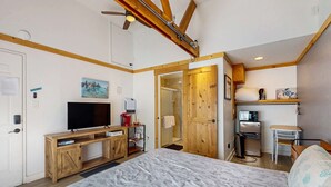 Une chambre à coucher comprenant un lit, des meubles en bois, une télévision, un four à micro-ondes et une douche.