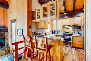 Ein Holzinnenraum mit Küche, Bar und Kamin aus Stein.