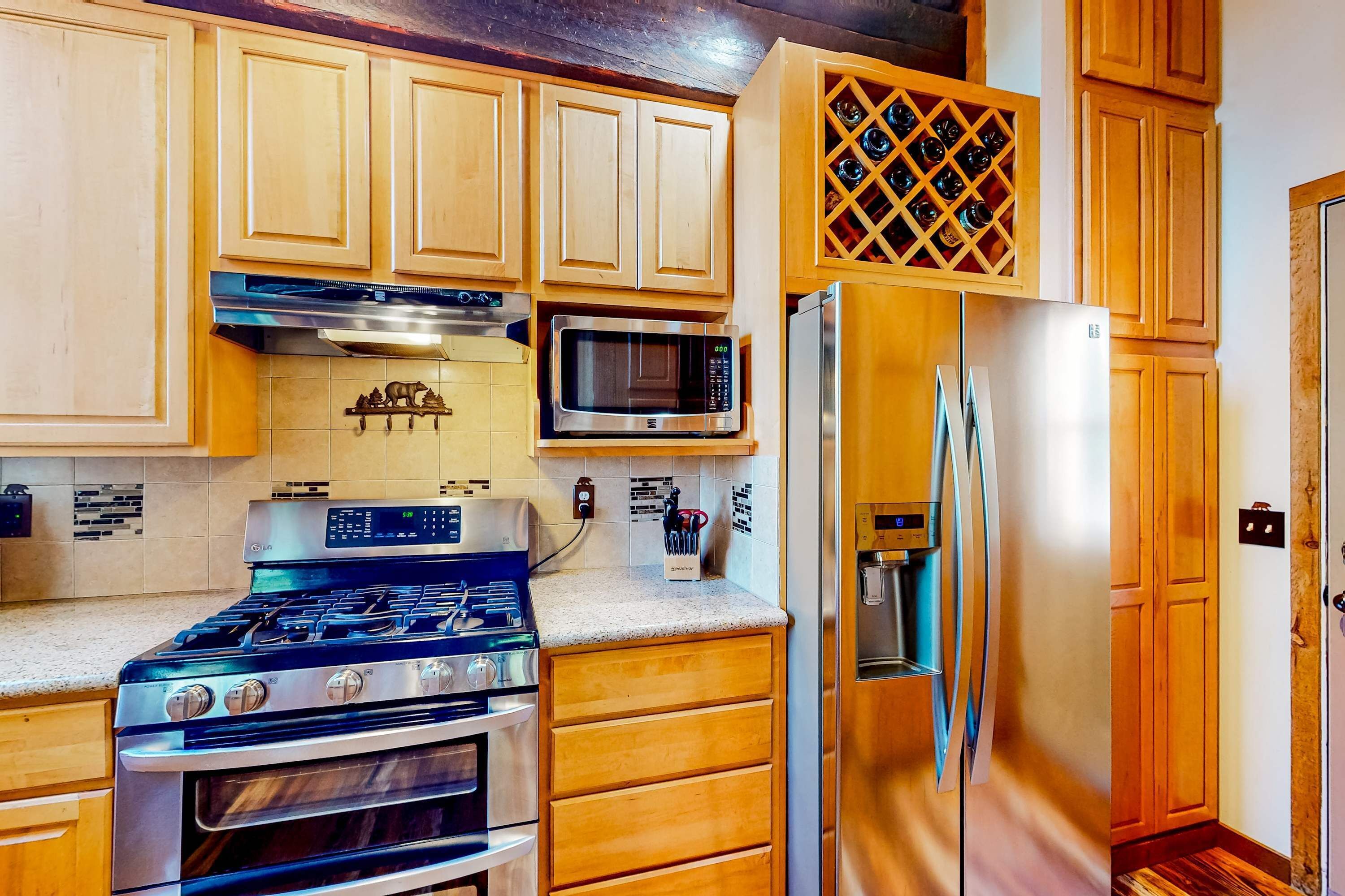 A kitchen with wooden cabinets, a stainless steel stove, a microwave, and a refrigerator.