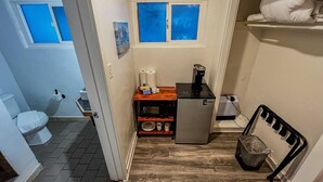 Ein kleines Badezimmer mit Toilette, einem Handwaschbecken und einem kompakten Kühlschrank.