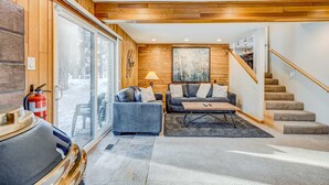 Ein modernes Wohnzimmer mit Kamin, einer Couch, einem Couchtisch und einer Treppe.