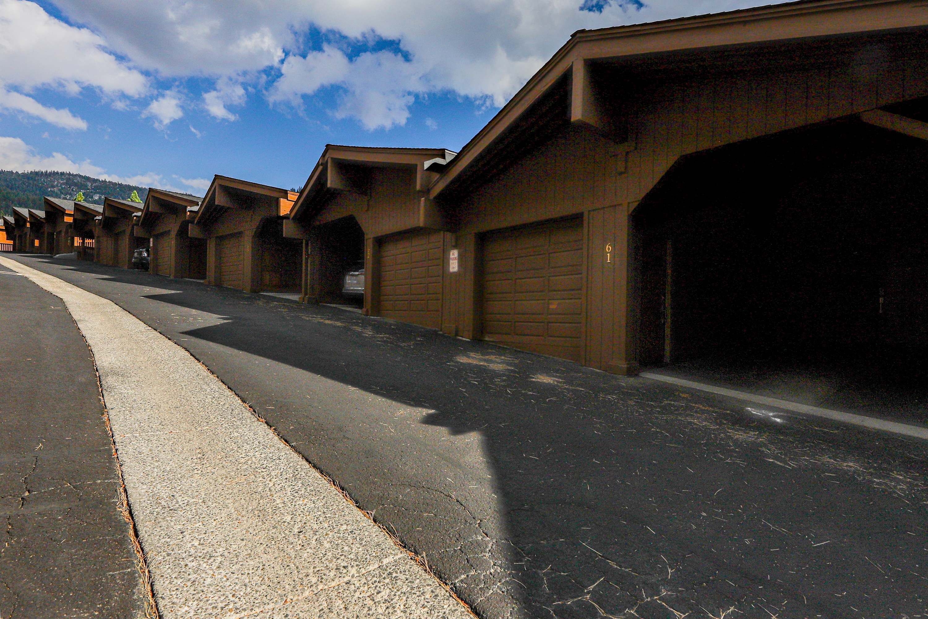 A row of garage-style buildings with a paved road in front.