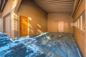 Un porche abrité avec des murs et des portes en bois, un plancher dégagé et une porte de garage visible.