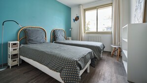A bedroom with two beds, a window, a radiator, and a desk. - Balcony facing Pontaillac beach, garage, sleeps 4. (Royan)