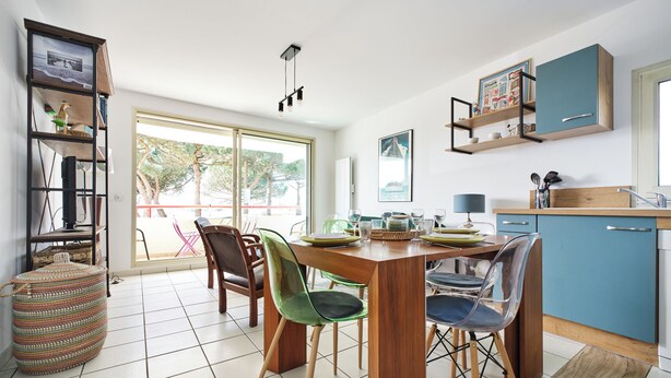A modern kitchen with a dining table, chairs, and a blue cabinet. - Balcony facing Pontaillac beach, garage, sleeps 4. (Royan)