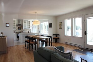 Un grand espace de vie comprenant un canapé, une table à manger avec des chaises et une cuisine à l’arrière-plan.