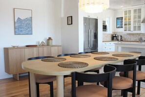 Une cuisine moderne dotée d’un îlot central, d’une table à manger avec des sets de table et d’un réfrigérateur.