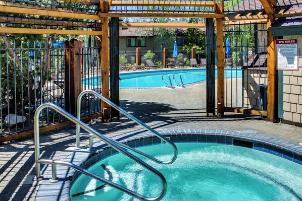 A pool area with a metal ladder, lounge chairs, and a wooden pergola structure. - Bright condo with outdoor pool, hot tub, tennis, sauna & patio - walk to lake (Tahoe City)