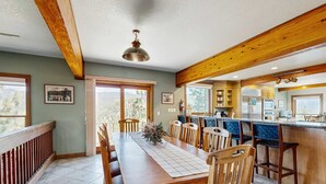 A dining area with a wooden table, chairs, and a view of the kitchen. - Lake- & mountain-view lodge with hot tub, rooftop deck & pool table, sleeps 10 (Zephyr Cove)
