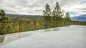 A concrete terrace with a metal railing, overlooking a mountainous landscape with trees. - Lake- & mountain-view lodge with hot tub, rooftop deck & pool table, sleeps 10 (Zephyr Cove)