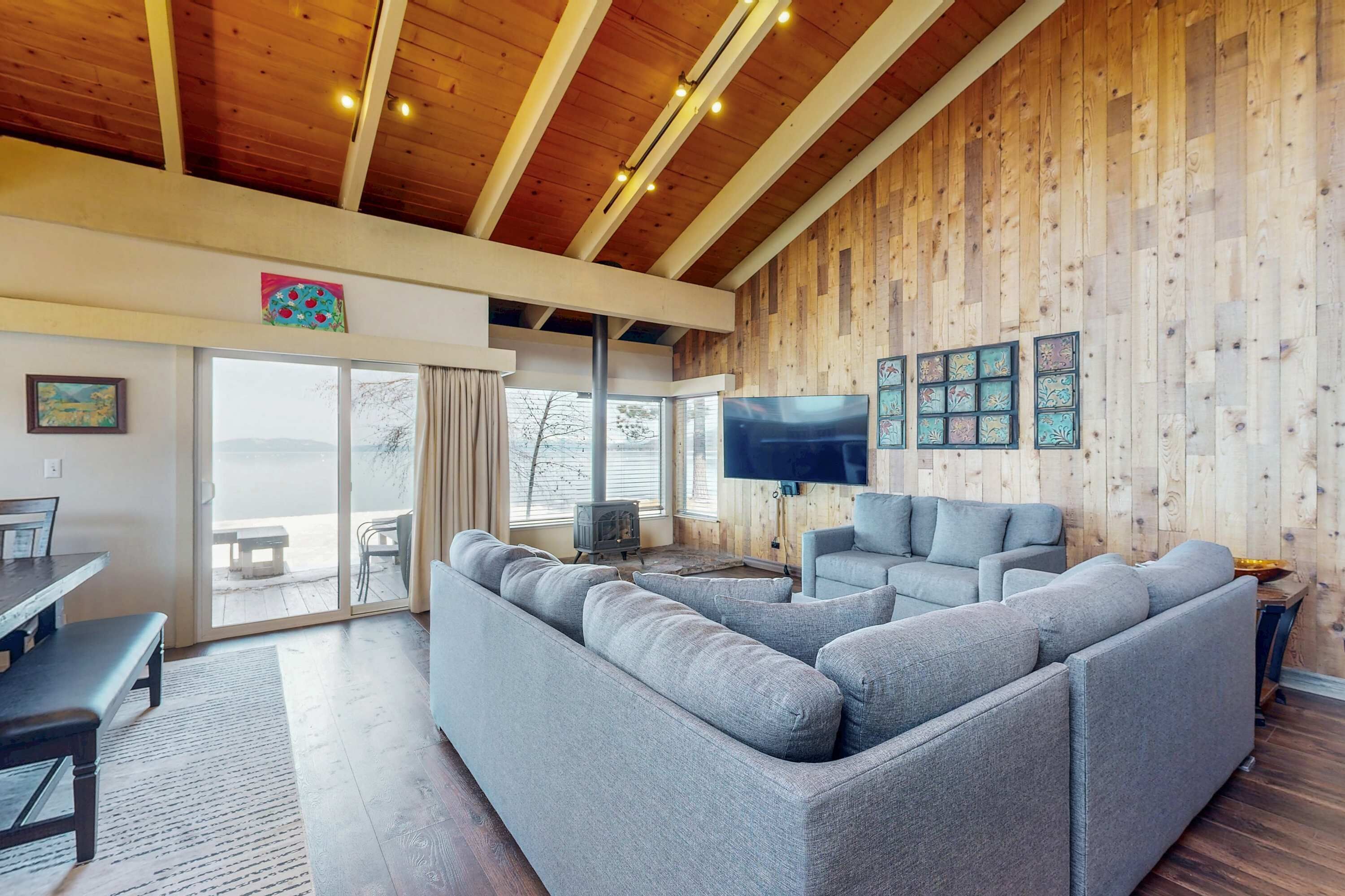 Uma sala de estar moderna com um sofá seccional grande, uma televisão de tela plana e painéis de parede de madeira.