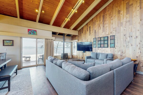 Ein modernes Wohnzimmer mit einer großen Eckcouch, einem Flachbildfernseher und Wandverkleidungen aus Holz.