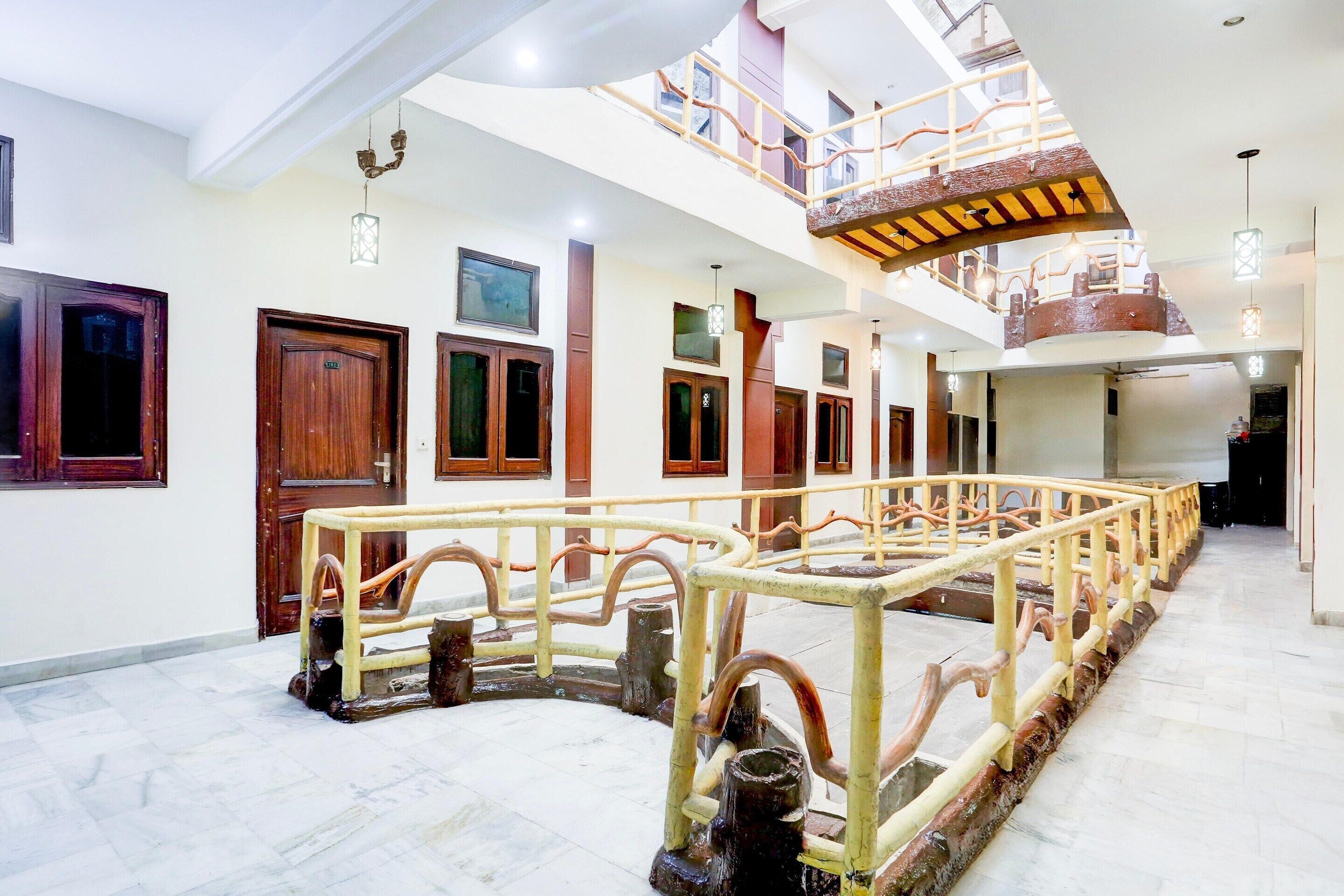 A hotel interior with a central water feature, wooden doors, and a staircase leading to an upper level.