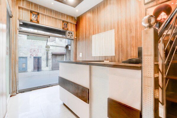 A reception area with a wooden panel wall, a reception desk, and a view of the street outside.