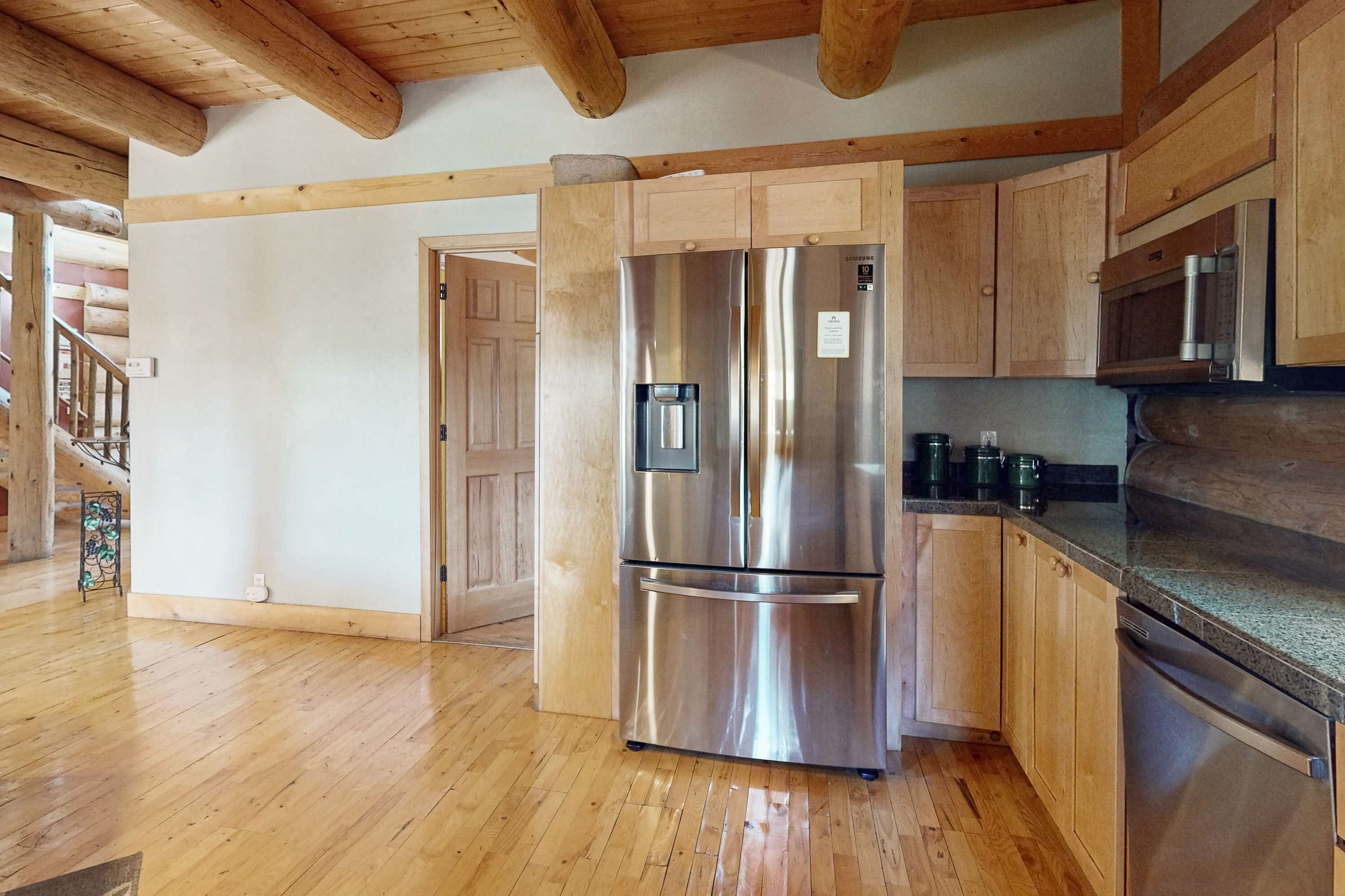 A kitchen with wooden cabinets, a stainless steel refrigerator, a microwave, and a dishwasher.