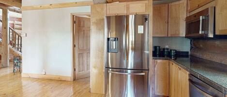 A kitchen with wooden cabinets, a stainless steel refrigerator, a microwave, and a dishwasher.