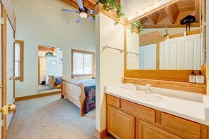 A bedroom with a bed, a wooden dresser, a large mirror, and a ceiling fan. - Condo with private balcony, gas fireplace, & washer&dryer (Truckee)