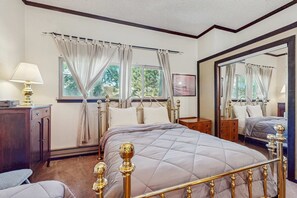 Une chambre à coucher avec un lit, une table de chevet, une lampe, une fenêtre avec des rideaux et un miroir.