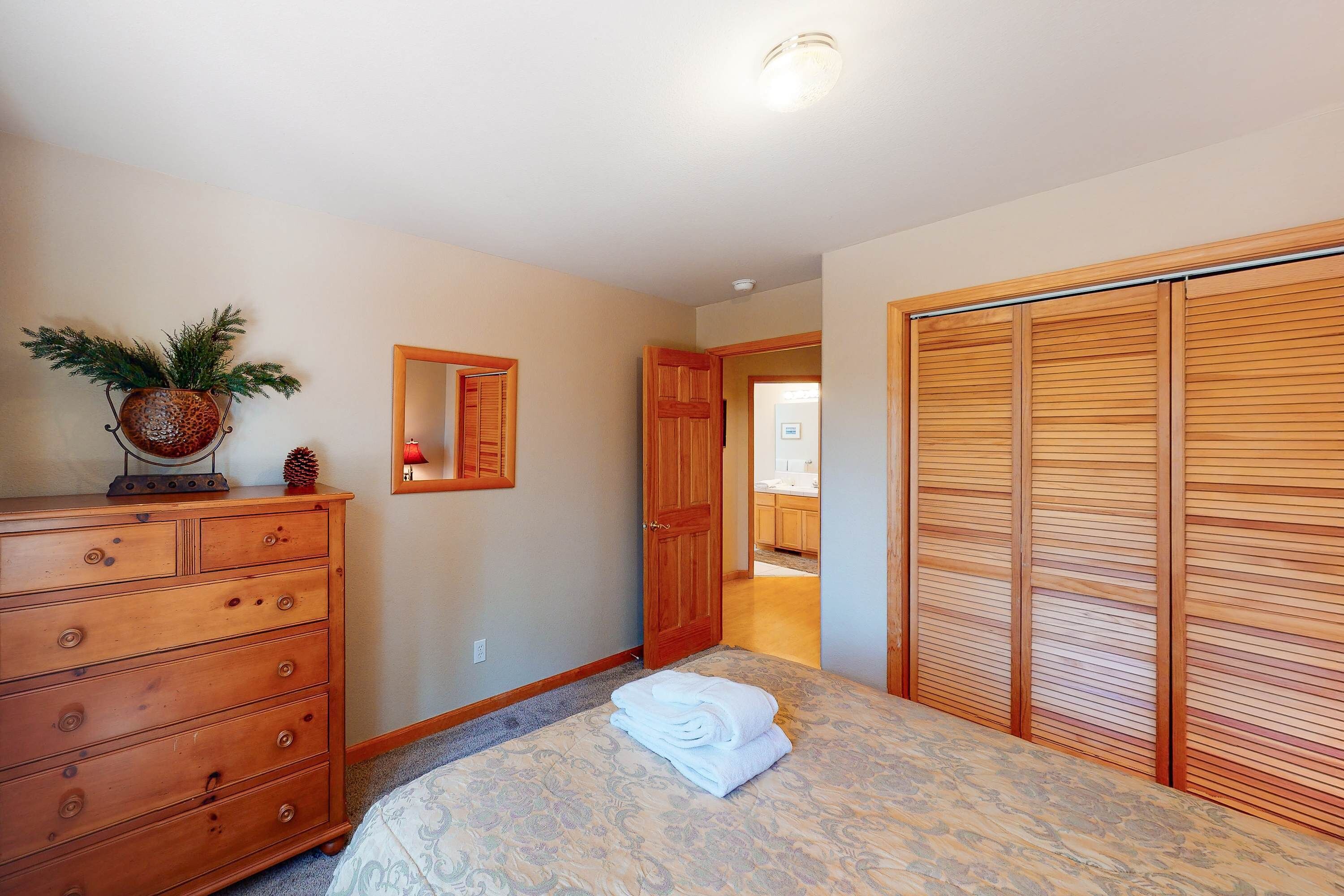 Een slaapkamer met een bed, een houten dressoir en een kast.