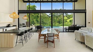 Une cuisine moderne avec un coin bar, de grandes fenêtres et une vue sur la piscine.