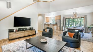 Een moderne woonkamer met een flatscreen televisie, een salontafel van donker hout en twee grijze banken.