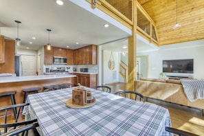 A modern kitchen with wooden cabinets, stainless steel appliances, and a dining area with a plaid tablecloth. - Charming cabin near downtown Truckee & skiing with large deck (Truckee)