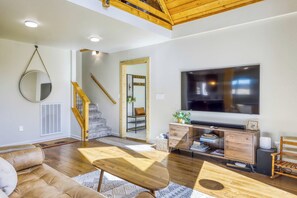 A modern living room with a wooden staircase, a flat-screen TV, and a comfortable seating area. - Charming cabin near downtown Truckee & skiing with large deck (Truckee)