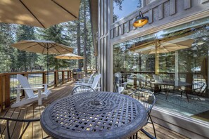 An outdoor deck with tables and chairs, surrounded by glass walls offering views of trees. - Charming cabin near downtown Truckee & skiing with large deck (Truckee)