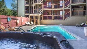 A swimming pool with lounge chairs, a hot tub, and a multi-story building with balconies. - Mountain Condo with  Shared Hot Tub & Pool, High-Speed WiFi, & Private washer & dryer (Park City)
