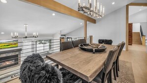 Et moderne spiseområde med et træbord, læderstole og en lysekrone.