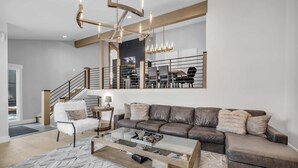 En moderne stue med et glas sofabord, en lædersofa og en trappe med gelænder.
