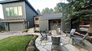 Et moderne hus med en stenbelagt terrasse, udendørs møbler og en garage.