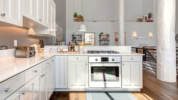 Een moderne keuken met witte kasten, een Bosch oven en hangende lampen.
