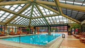 An indoor swimming pool with a glass ceiling, lounge chairs, and a tiled floor. - ski-in - ski-out Condo with  Shared Hot Tubs & Pool, High-Speed WiFi, & Central AC (Park City)