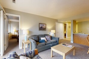 A living room with a sofa, coffee table, and a painting on the wall. - Mountain-view condo with fireplace, near skiing & main street, on shuttle route (Park City)