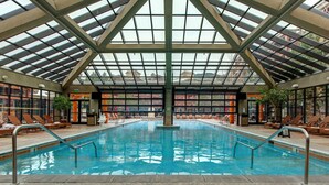 Una piscina interior con techo de vidrio, sillas de descanso y un cartel que indica 'NO DIVING'.